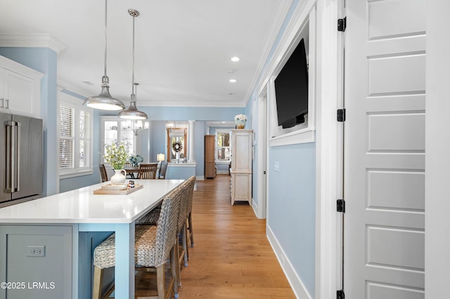 kitchen featuring pendant lighting, a breakfast bar area, white cabinetry, ornamental molding, and a kitchen island