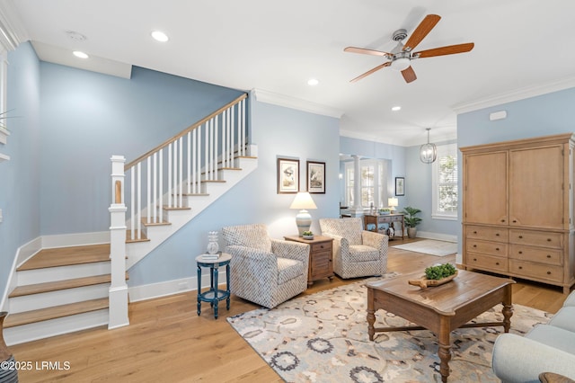 living room with ornamental molding, ceiling fan, and light hardwood / wood-style flooring