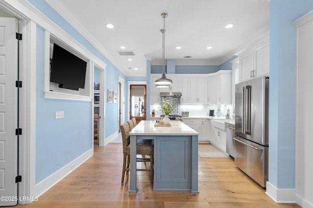 kitchen with white cabinets, a kitchen breakfast bar, hanging light fixtures, a center island, and stainless steel appliances