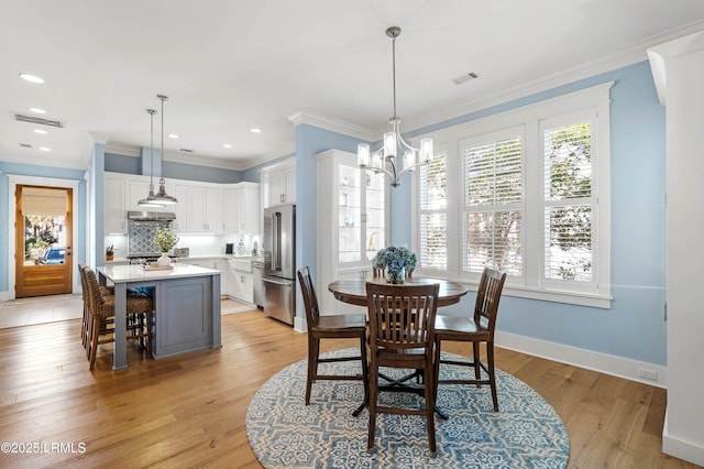 dining room with crown molding, a notable chandelier, and light hardwood / wood-style floors