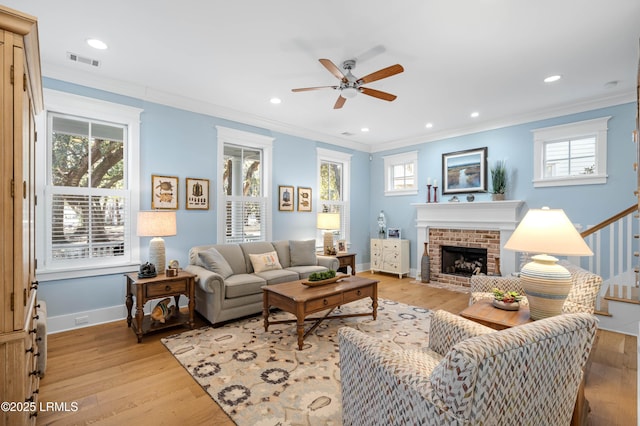 living room with crown molding, ceiling fan, a fireplace, and light hardwood / wood-style flooring