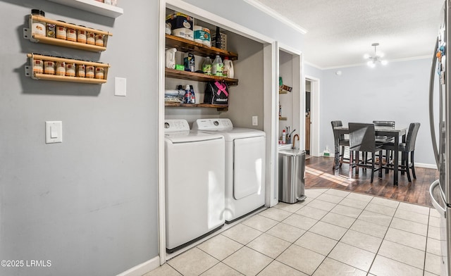 laundry area featuring crown molding, washing machine and dryer, a textured ceiling, and light tile patterned floors