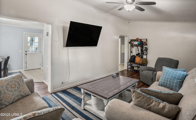 living room with a textured ceiling, light hardwood / wood-style flooring, ornamental molding, and ceiling fan