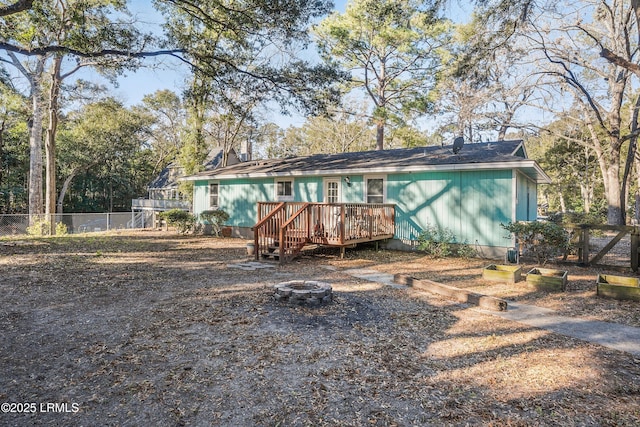 back of property with a deck and an outdoor fire pit