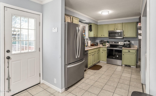 kitchen with a textured ceiling, light tile patterned floors, ornamental molding, appliances with stainless steel finishes, and green cabinets