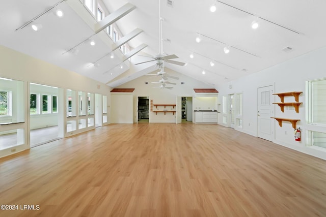 unfurnished living room featuring high vaulted ceiling, light hardwood / wood-style floors, rail lighting, and ceiling fan