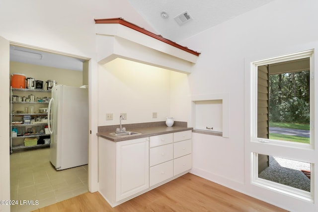 kitchen with white cabinetry, sink, white fridge, and light wood-type flooring