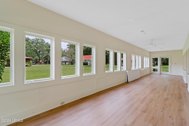 unfurnished sunroom featuring ceiling fan and a healthy amount of sunlight