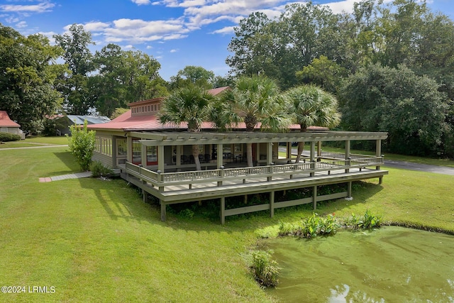 rear view of property featuring a deck with water view and a lawn