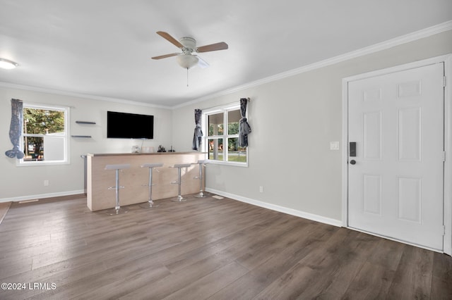 unfurnished living room with ceiling fan, ornamental molding, and dark hardwood / wood-style floors