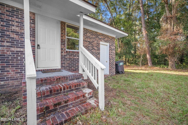 view of exterior entry featuring a lawn