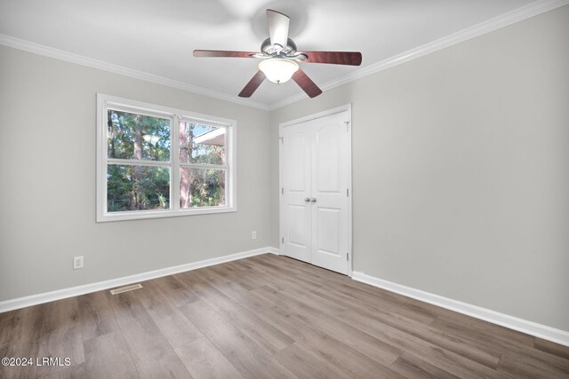 unfurnished bedroom featuring crown molding, light hardwood / wood-style floors, a closet, and ceiling fan