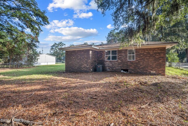 rear view of house featuring cooling unit and a yard