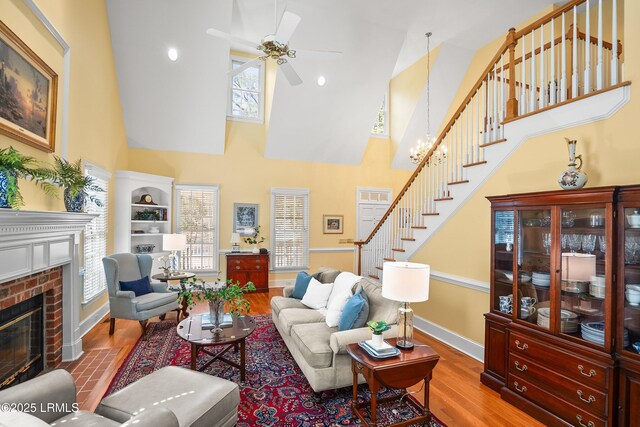living room featuring plenty of natural light, stairway, a fireplace, and wood finished floors