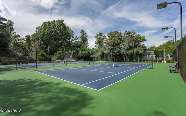 view of tennis court featuring fence and community basketball court