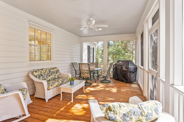 sunroom / solarium with a deck, outdoor dining space, a ceiling fan, and wood-type flooring