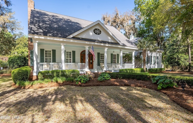 greek revival inspired property featuring a chimney, a porch, and roof with shingles