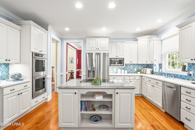 kitchen featuring appliances with stainless steel finishes, light wood-style flooring, white cabinets, decorative backsplash, and ornamental molding