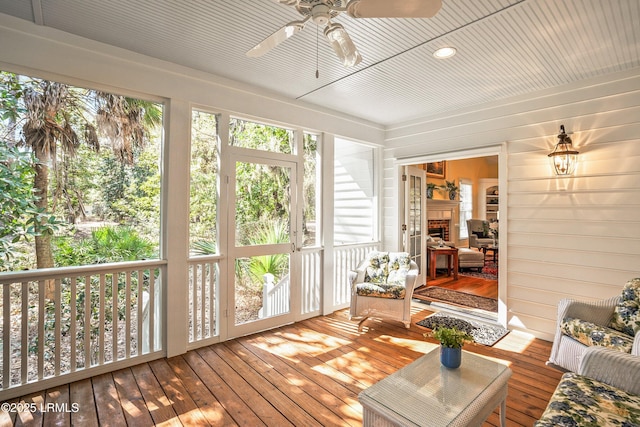 unfurnished sunroom featuring a fireplace and ceiling fan