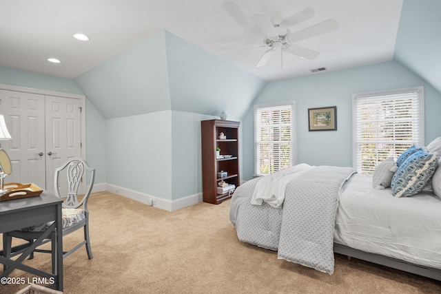carpeted bedroom with vaulted ceiling, a closet, baseboards, visible vents, and ceiling fan