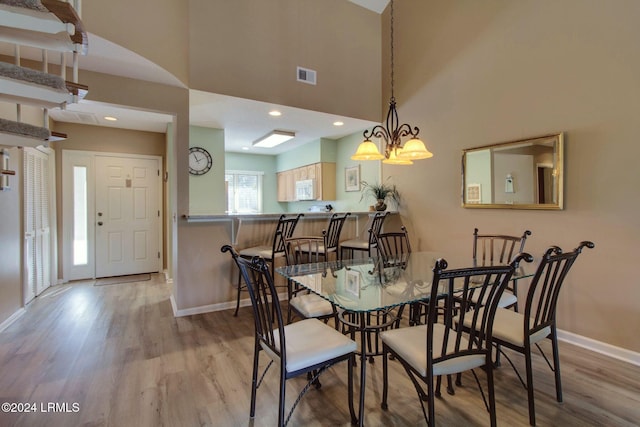 dining space with a high ceiling and light wood-type flooring