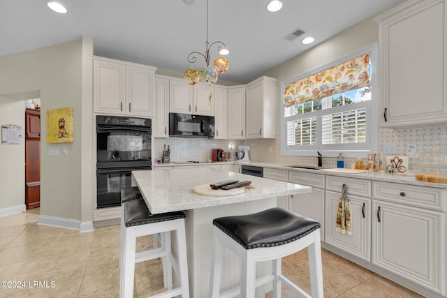 kitchen featuring hanging light fixtures, white cabinetry, light stone counters, and black appliances