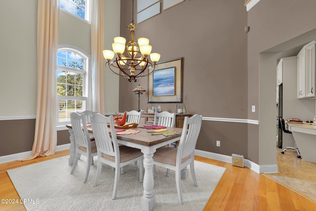 dining room featuring an inviting chandelier, light hardwood / wood-style floors, and a high ceiling