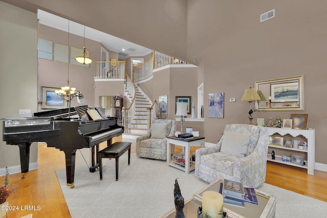 sitting room with hardwood / wood-style flooring, a chandelier, and a high ceiling