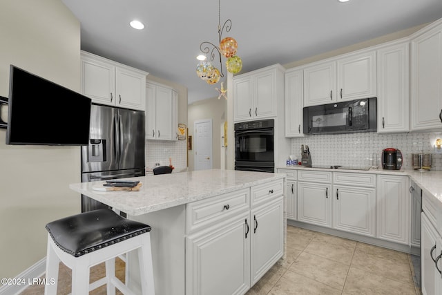 kitchen featuring white cabinetry, pendant lighting, black appliances, and a kitchen bar