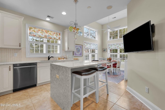 kitchen with white cabinetry, stainless steel dishwasher, hanging light fixtures, and a kitchen island