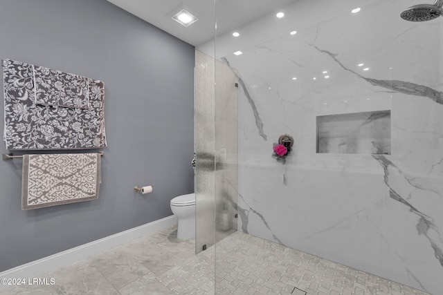 bathroom with a tile shower and toilet