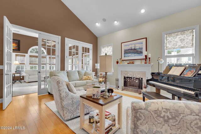 living room featuring light hardwood / wood-style flooring, a high end fireplace, french doors, and a healthy amount of sunlight