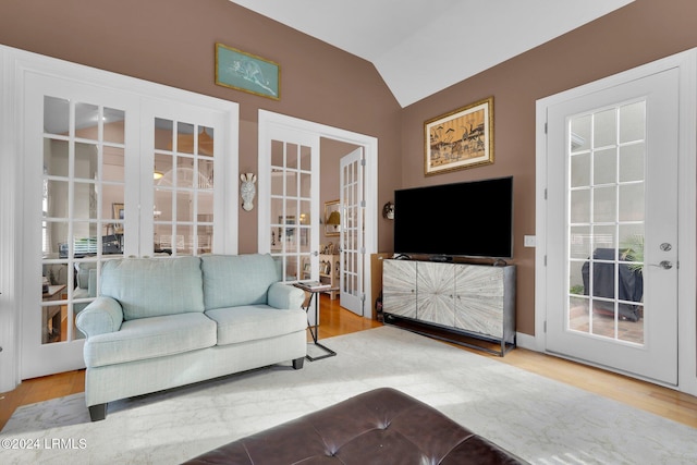 living room with vaulted ceiling, light wood-type flooring, and french doors