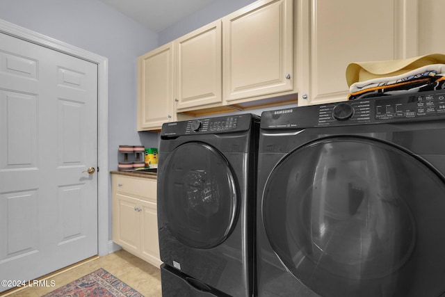 washroom with cabinets, washing machine and dryer, and light tile patterned flooring