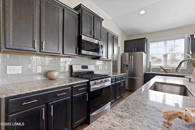 kitchen featuring ornamental molding, decorative backsplash, a sink, light stone countertops, and appliances with stainless steel finishes