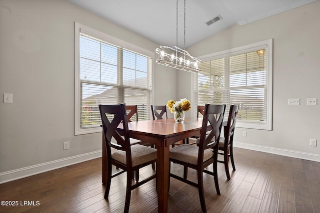 dining room featuring a chandelier, dark wood finished floors, lofted ceiling, baseboards, and visible vents