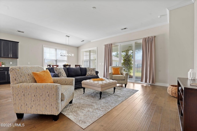 living room featuring baseboards, a notable chandelier, visible vents, and wood finished floors