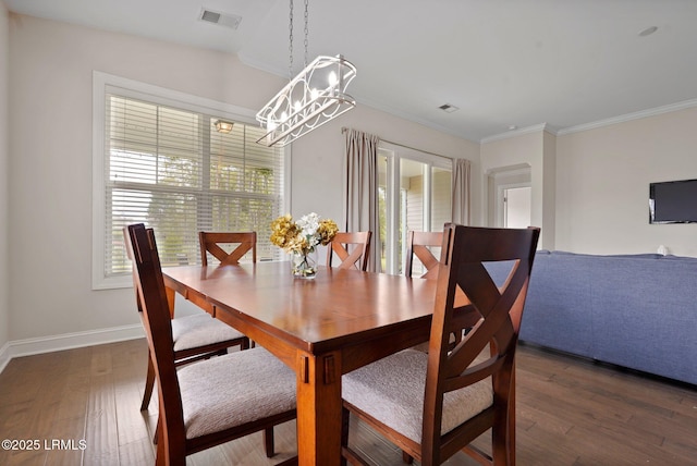 dining area featuring visible vents, baseboards, ornamental molding, wood finished floors, and a notable chandelier