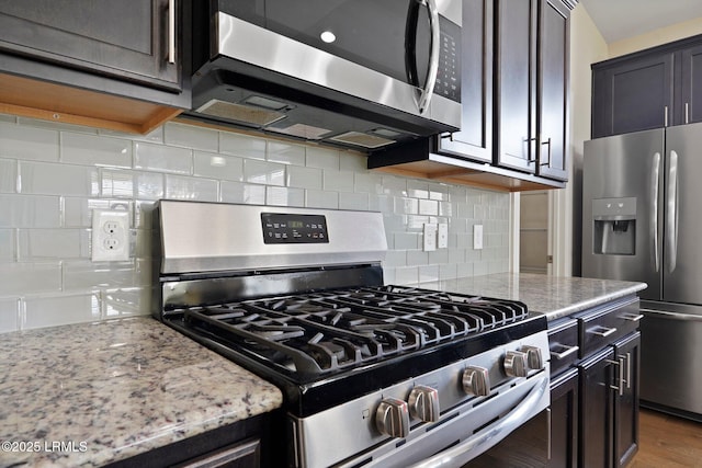 kitchen featuring wood finished floors, light stone counters, tasteful backsplash, and appliances with stainless steel finishes
