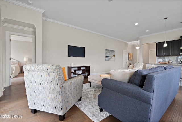 living area with baseboards, wood finished floors, recessed lighting, and crown molding