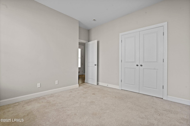 unfurnished bedroom with carpet floors, baseboards, and a closet