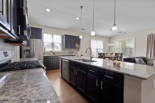 kitchen featuring dishwasher, a kitchen island with sink, wood finished floors, a sink, and gas range