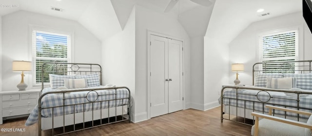 bedroom with lofted ceiling, visible vents, baseboards, and wood finished floors