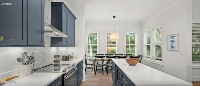 kitchen with decorative light fixtures, blue cabinets, stainless steel electric range, light countertops, and wall chimney range hood