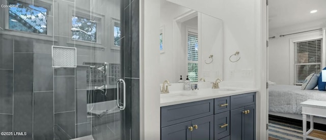 bathroom featuring double vanity, plenty of natural light, a shower stall, and a sink