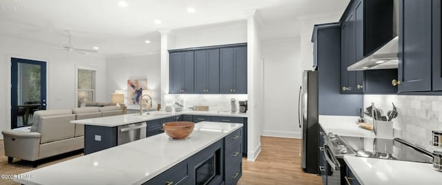kitchen featuring light wood finished floors, backsplash, appliances with stainless steel finishes, open floor plan, and a kitchen island