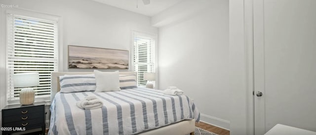 bedroom featuring a ceiling fan, baseboards, and wood finished floors