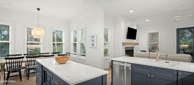 kitchen with dishwasher, a kitchen island, dark wood-type flooring, hanging light fixtures, and a fireplace