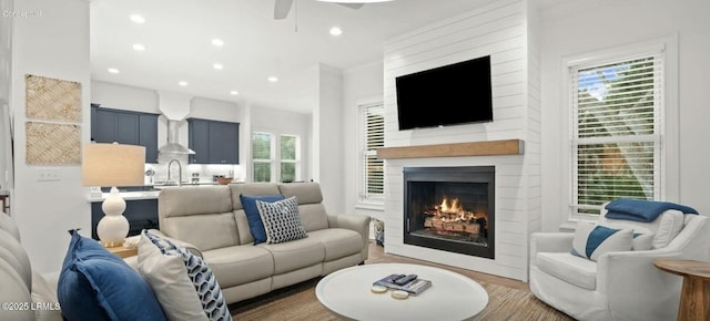 living area featuring a ceiling fan, recessed lighting, a fireplace, and wood finished floors
