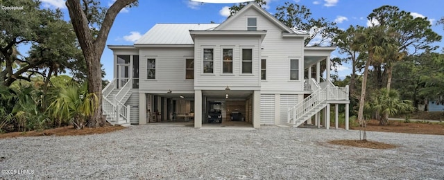beach home featuring a carport, gravel driveway, a sunroom, and metal roof